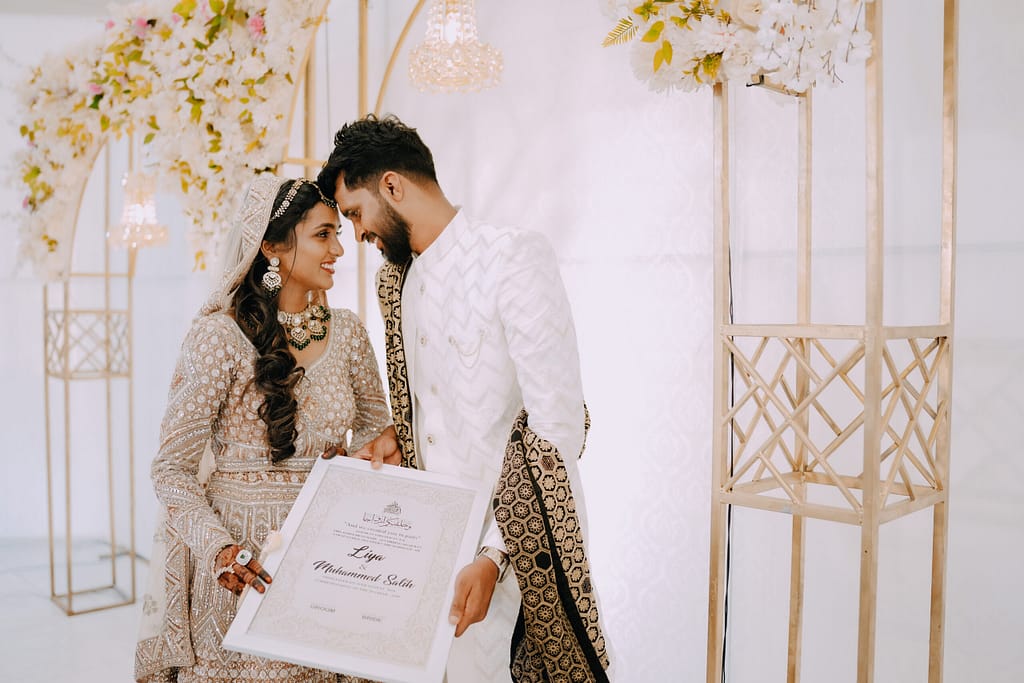 “Bride and groom kissing under a floral arch at a Wedding Photographers in Palakkad ”